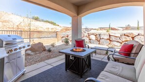 An outdoor patio with a barbecue grill, a table with a fire pit, and seating. - Arcade Adventure by RedAwning (Washington)