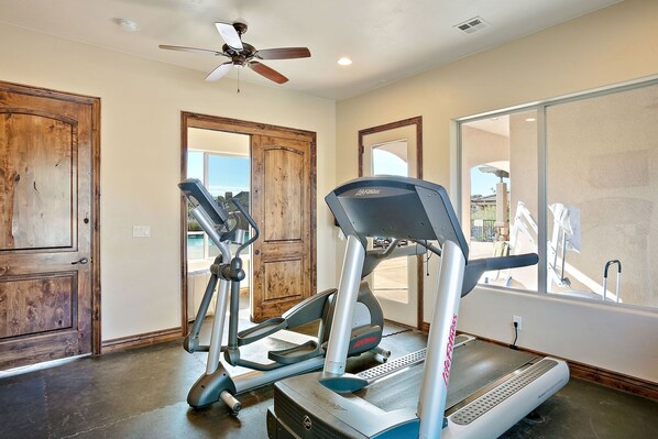 A home gym with treadmills and elliptical machines, wooden doors, and a large window. - Views for Rent by RedAwning (Washington)
