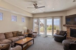 A living room with a sofa, armchairs, a coffee table, a TV, and a fireplace.