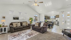 A spacious living room with a high ceiling, a ceiling fan, and a dining area with a kitchen in the background. - Mountain View by RedAwning (Washington)