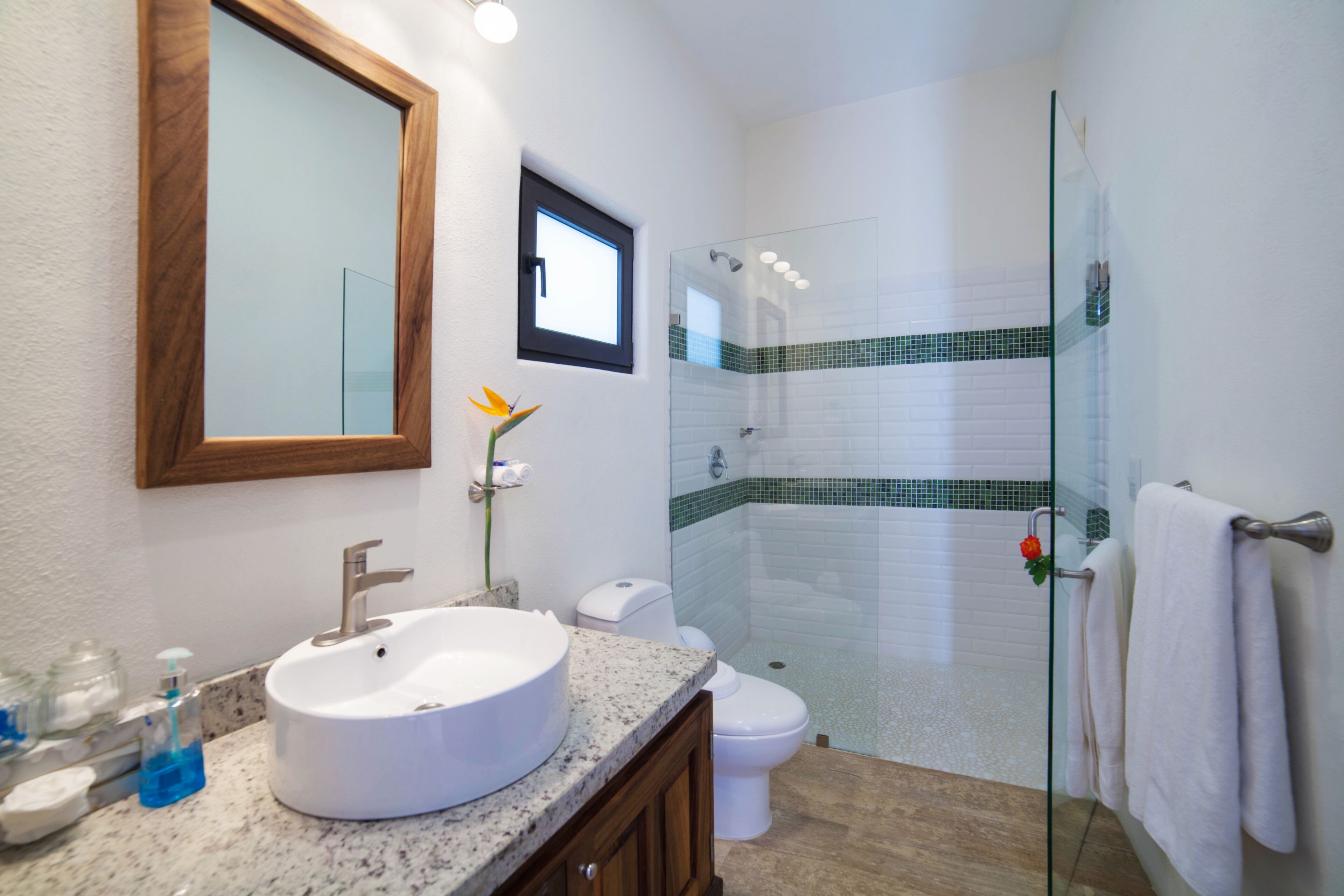 A bathroom with a large sink, toilet, and shower area.