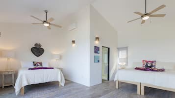 Un dormitorio moderno con dos camas, ventiladores de techo y un corazón decorativo en la pared.