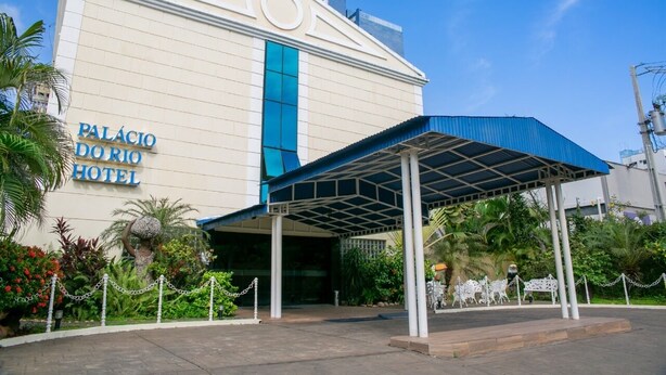 The exterior of the Palacio do Rio Hotel with a covered entrance and a chain-link fence. - Palacio do Rio Hotel (Teresina)