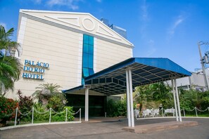 The exterior of the Palacio do Rio Hotel with a covered entrance and a chain-link fence.