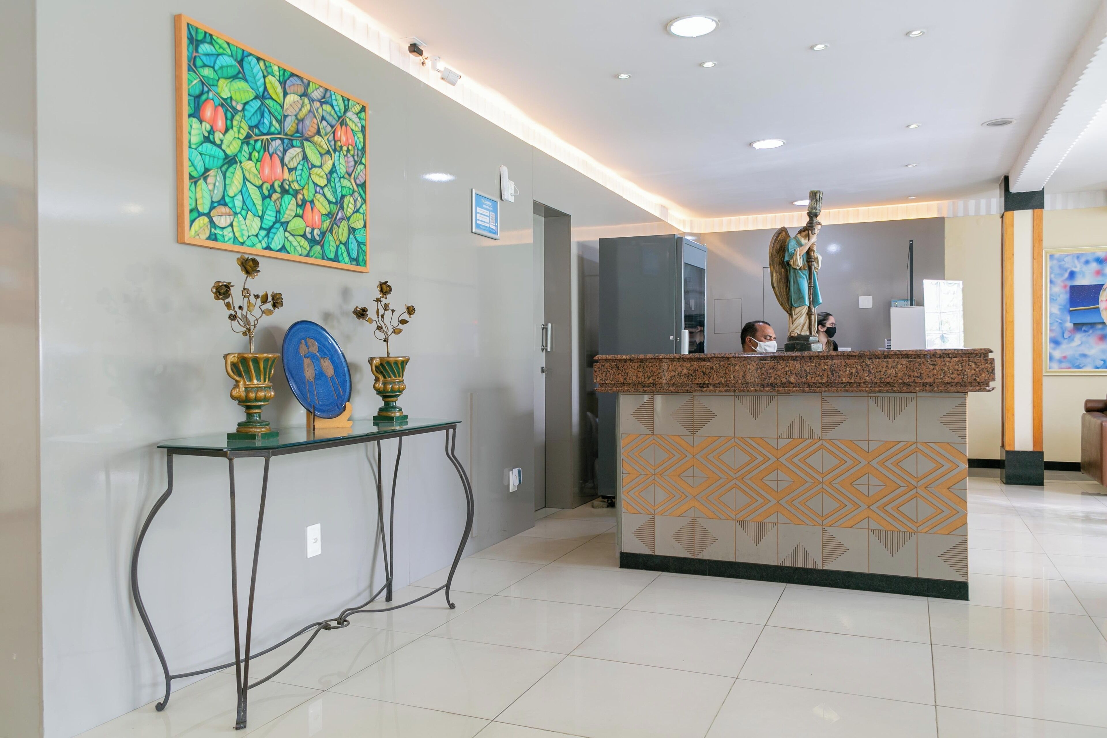 A reception area with a marble counter, a decorative plant, and a framed artwork on the wall.