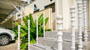A white car parked on a cobblestone driveway, white balustrades, and a building with a tiled facade. - Palacio do Rio Hotel (Teresina)