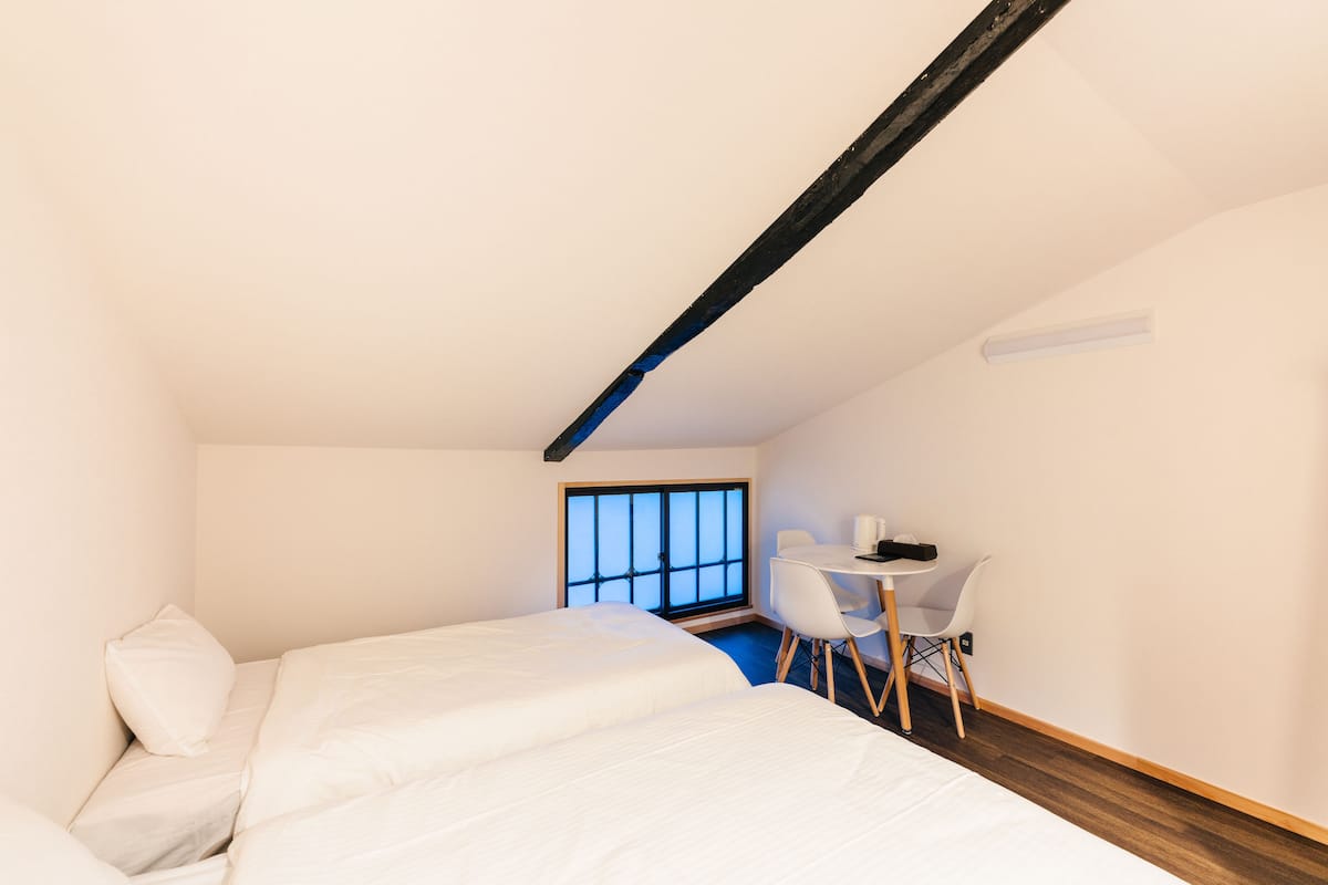 A bedroom with two beds, a desk, and a chair.