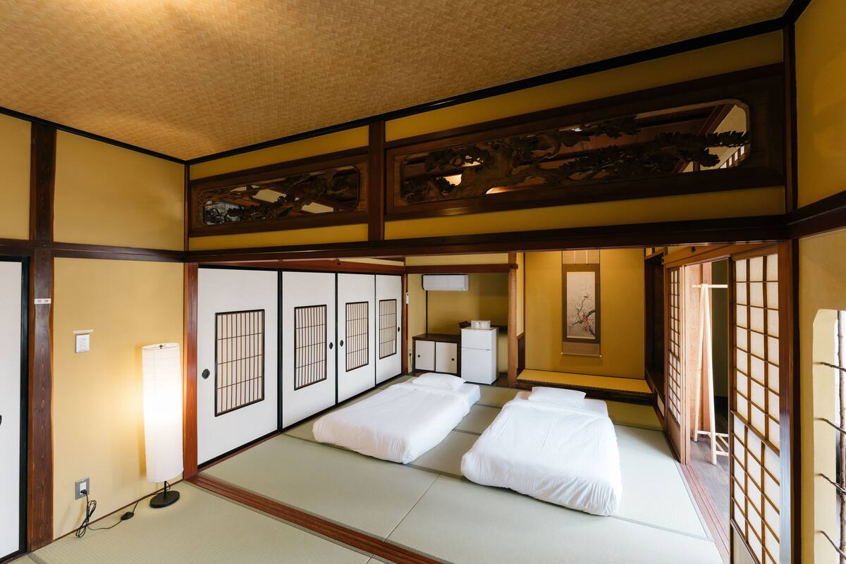 A traditional Japanese room with tatami flooring, shoji screens, and a futon bed arrangement.