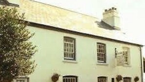 A white building with multiple windows and a door, likely a hotel or inn. - The Walkhampton Inn (Yelverton)