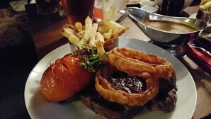 A plate with a steak, onion rings, and a baked potato. - The Walkhampton Inn (Yelverton)