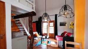 Un salon chaleureux avec une table en bois, un escalier et un canapé rouge.