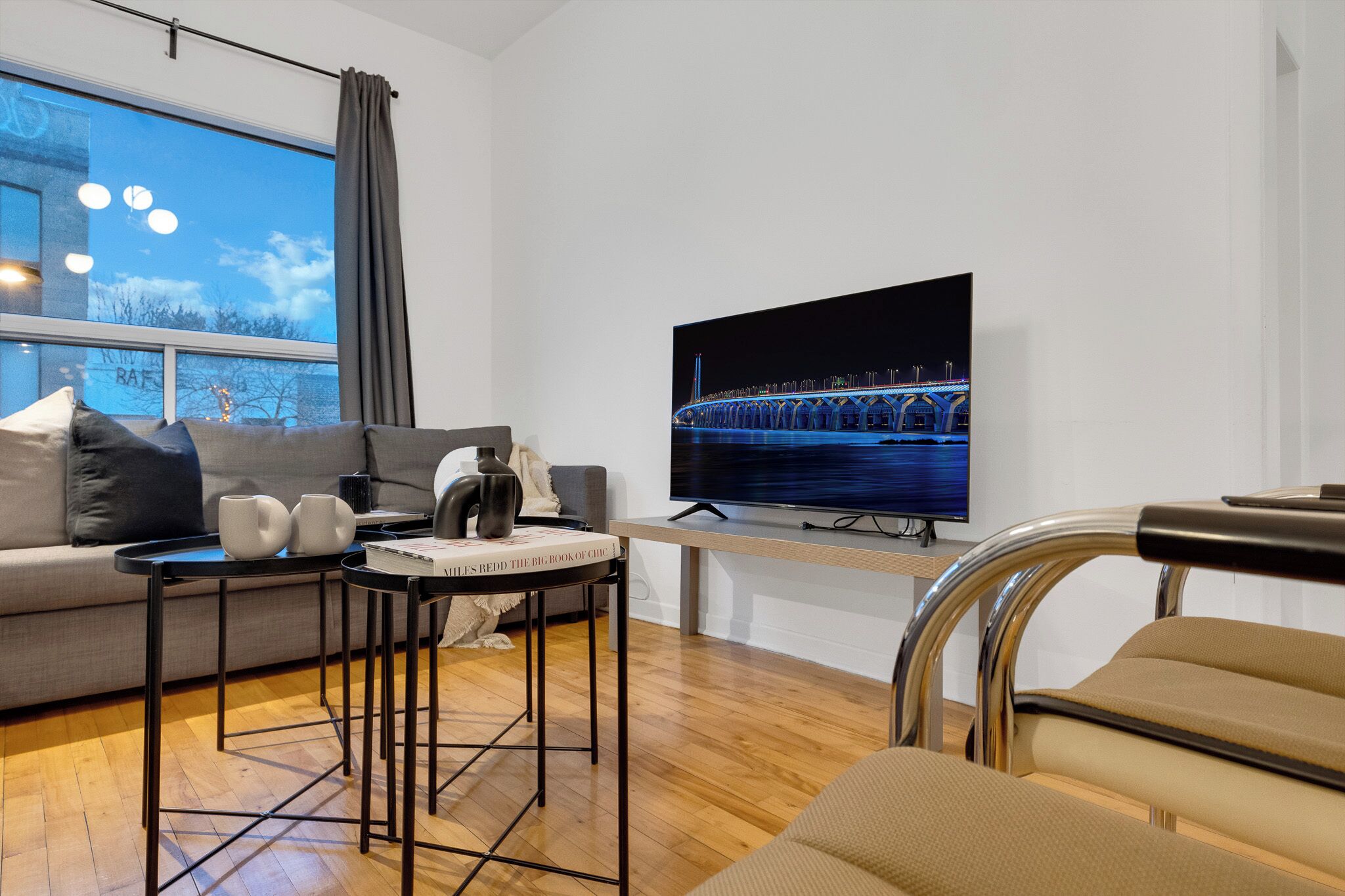 Een moderne woonkamer met een grote flatscreentelevisie, een bank, een salontafel en een fauteuil.
