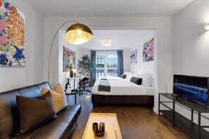A modern hotel room with a bed, sofa, TV, and artwork. - Lemon Stays​‌ - Avenue (Montreal)
