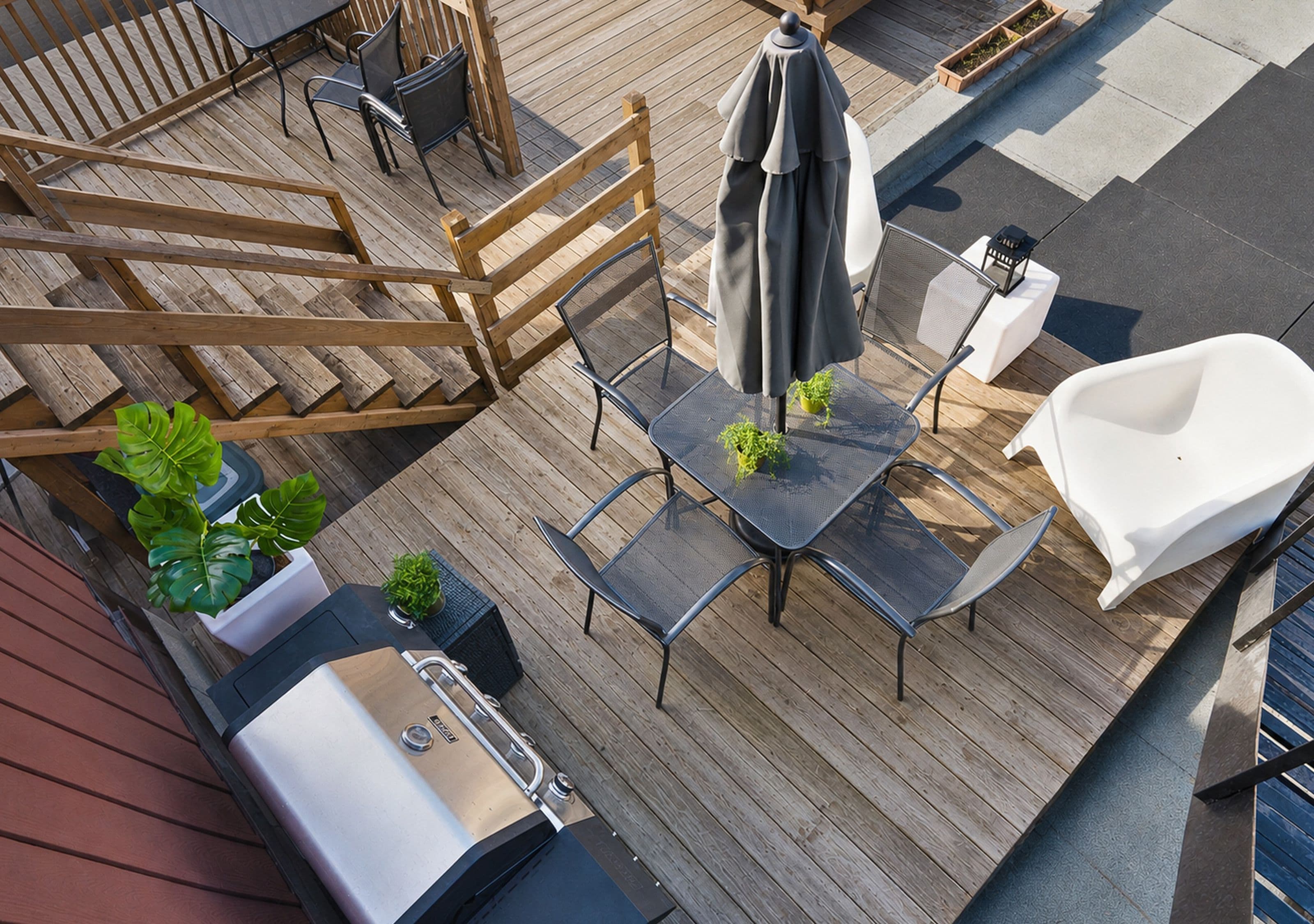 A deck with a grill, outdoor seating, and potted plants.