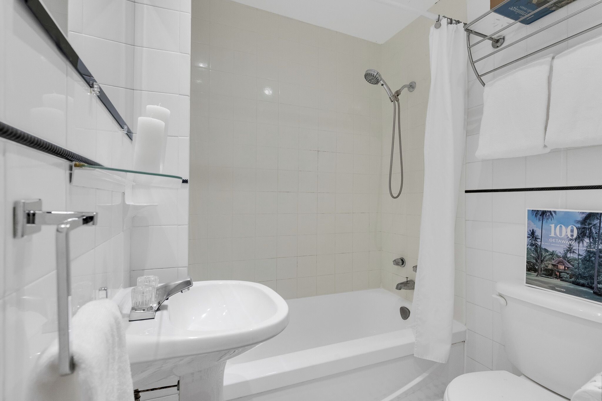 Un baño moderno con lavamanos, bañera y ducha blancos.