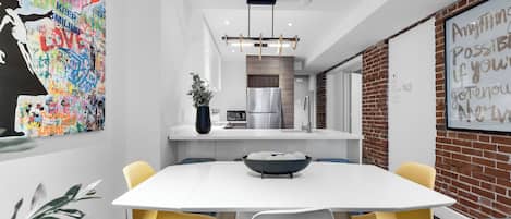 Una cocina moderna con encimera blanca, electrodomésticos de acero inoxidable y una lámpara colgante.