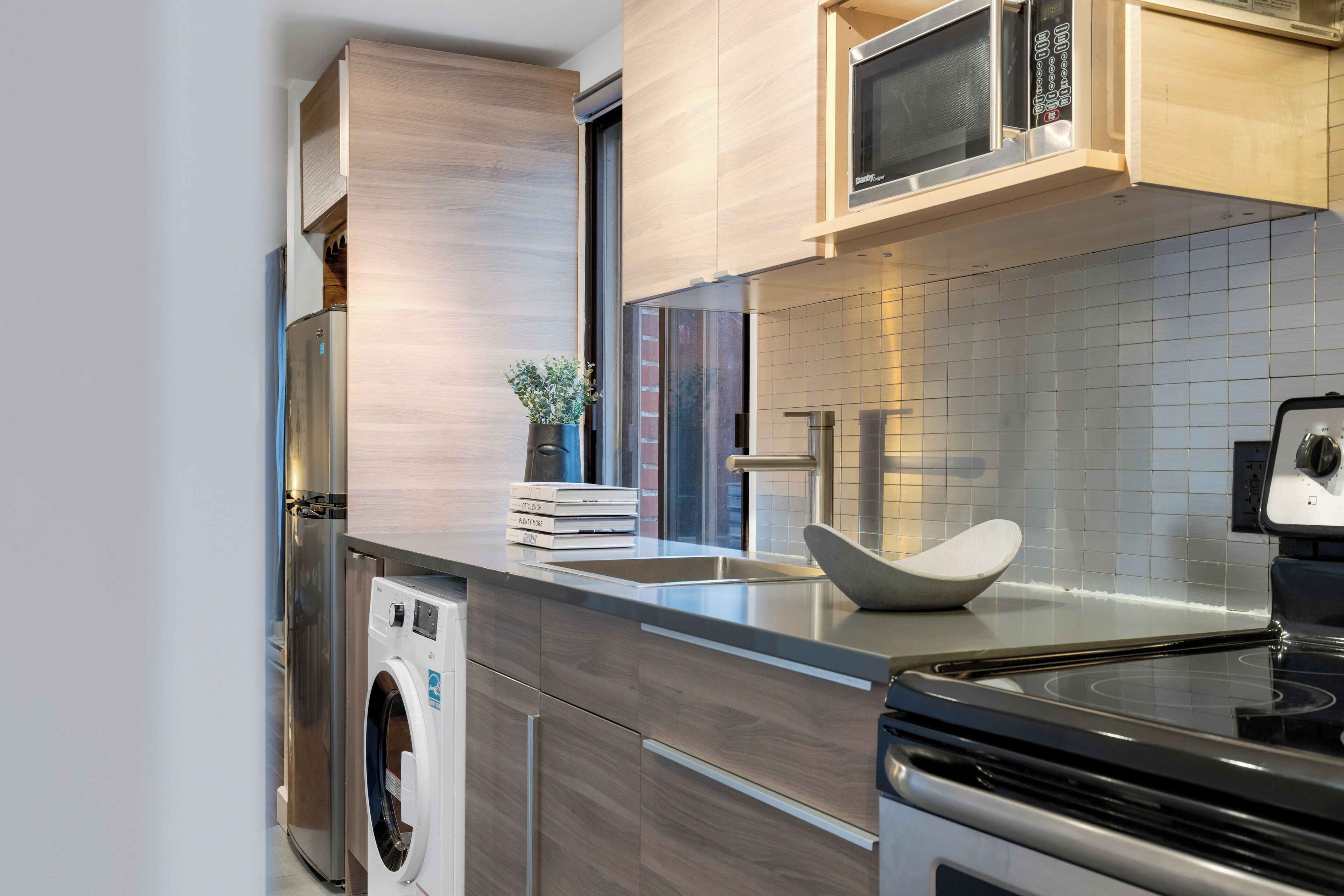 Una cocina moderna con electrodomésticos de acero inoxidable, lavadora integrada y un diseño de encimera elegante.