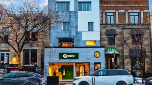Un edificio moderno con un'insegna 'SQDC', una vetrina e un SUV bianco parcheggiato.