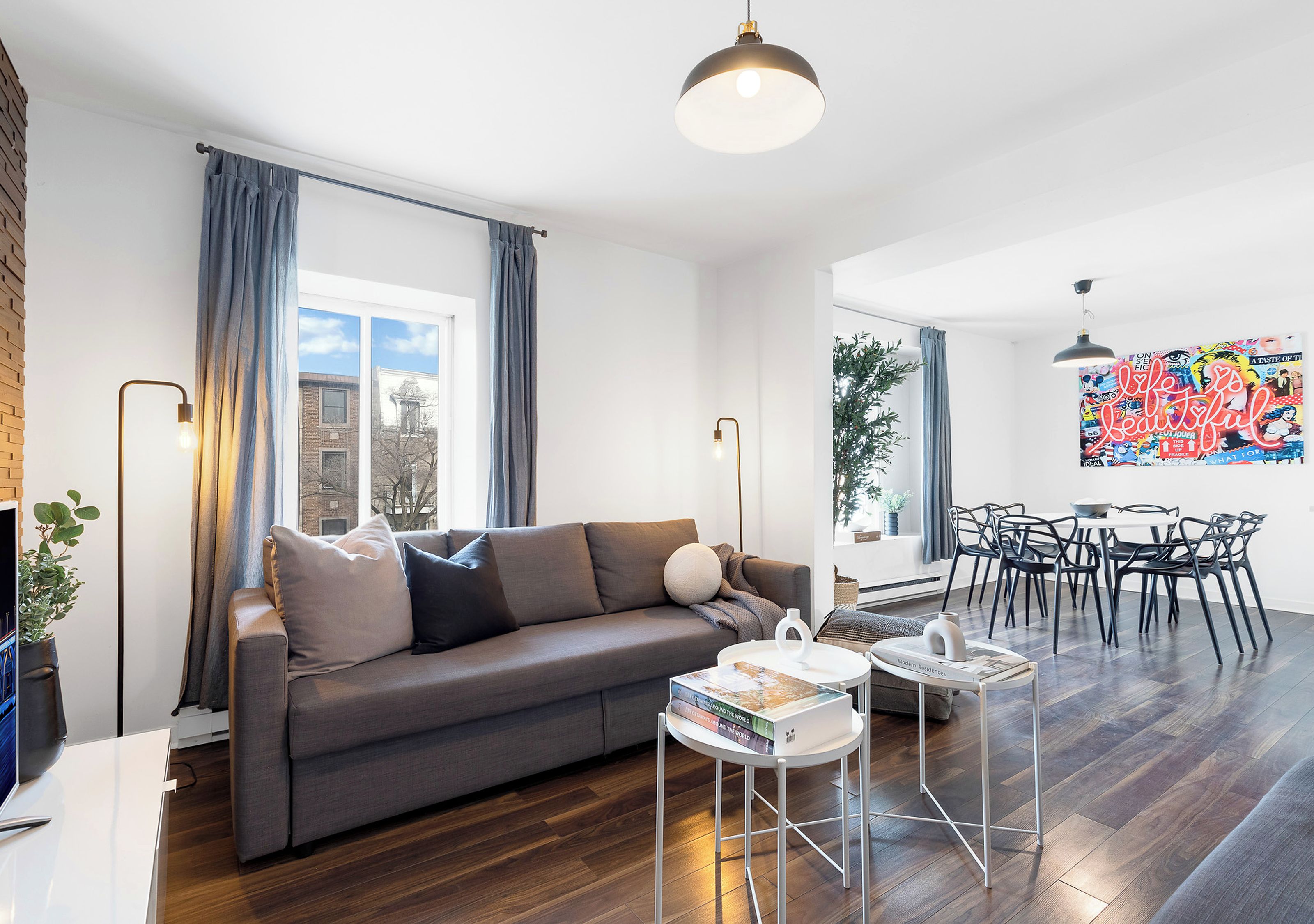 A modern living room with a sofa, coffee table, and a dining area with chairs.