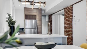 Una cucina moderna con un piano di lavoro bianco, elettrodomestici in acciaio inossidabile e una parete decorata con mattoni.