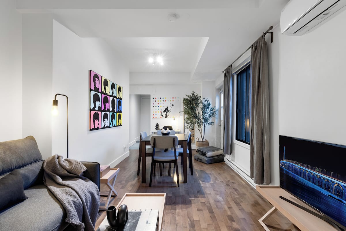 A modern living room with a sofa, a coffee table, a TV, and a dining area with a table and chairs.