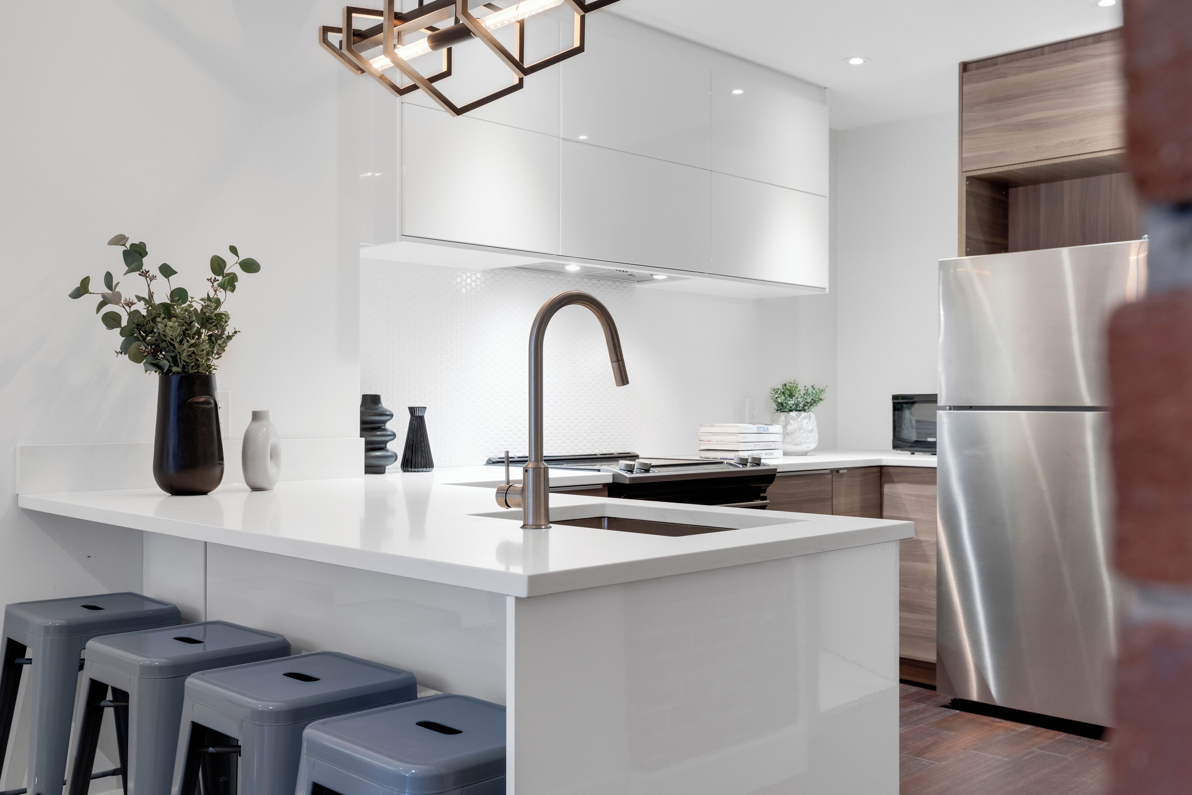 Une cuisine moderne dotée d’un îlot central, d’appareils électroménagers en acier inoxydable et de tabourets de bar.