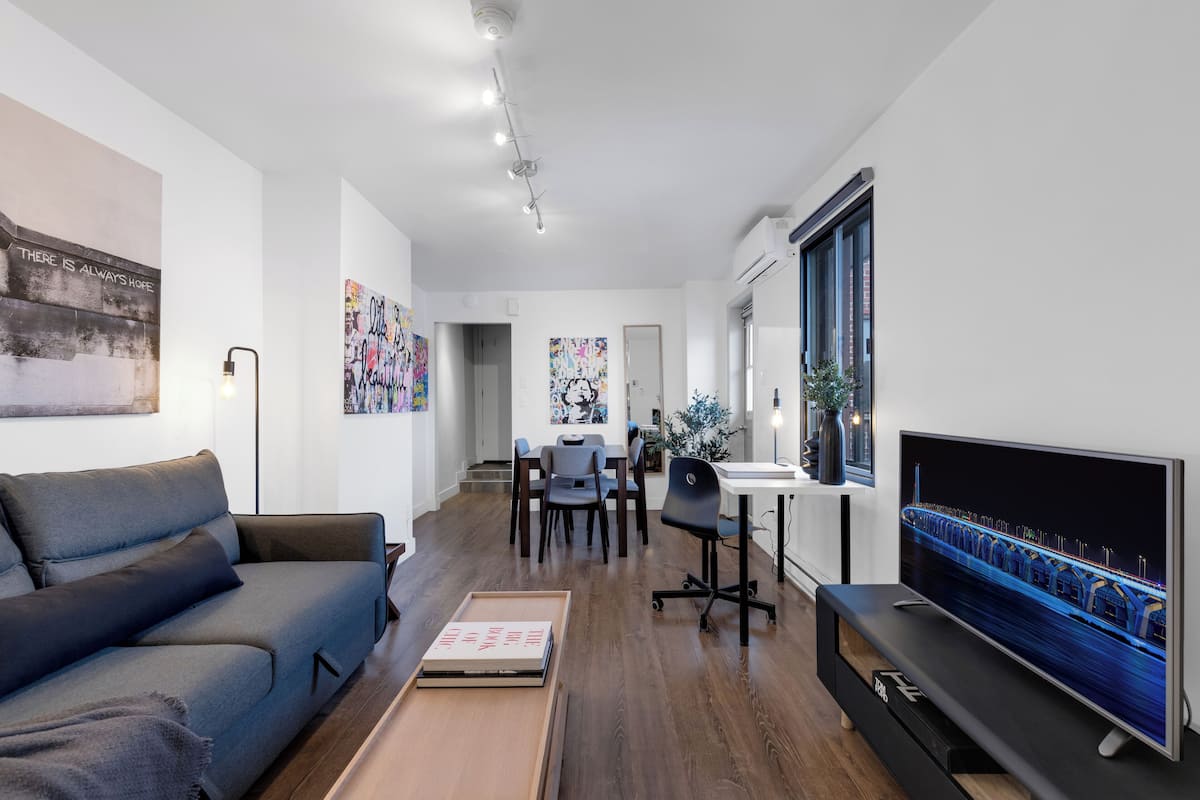 A modern living room with a sofa, TV, and artwork on the walls.