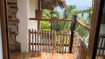 A wooden deck leading to a thatched-roof structure with a view of the ocean.