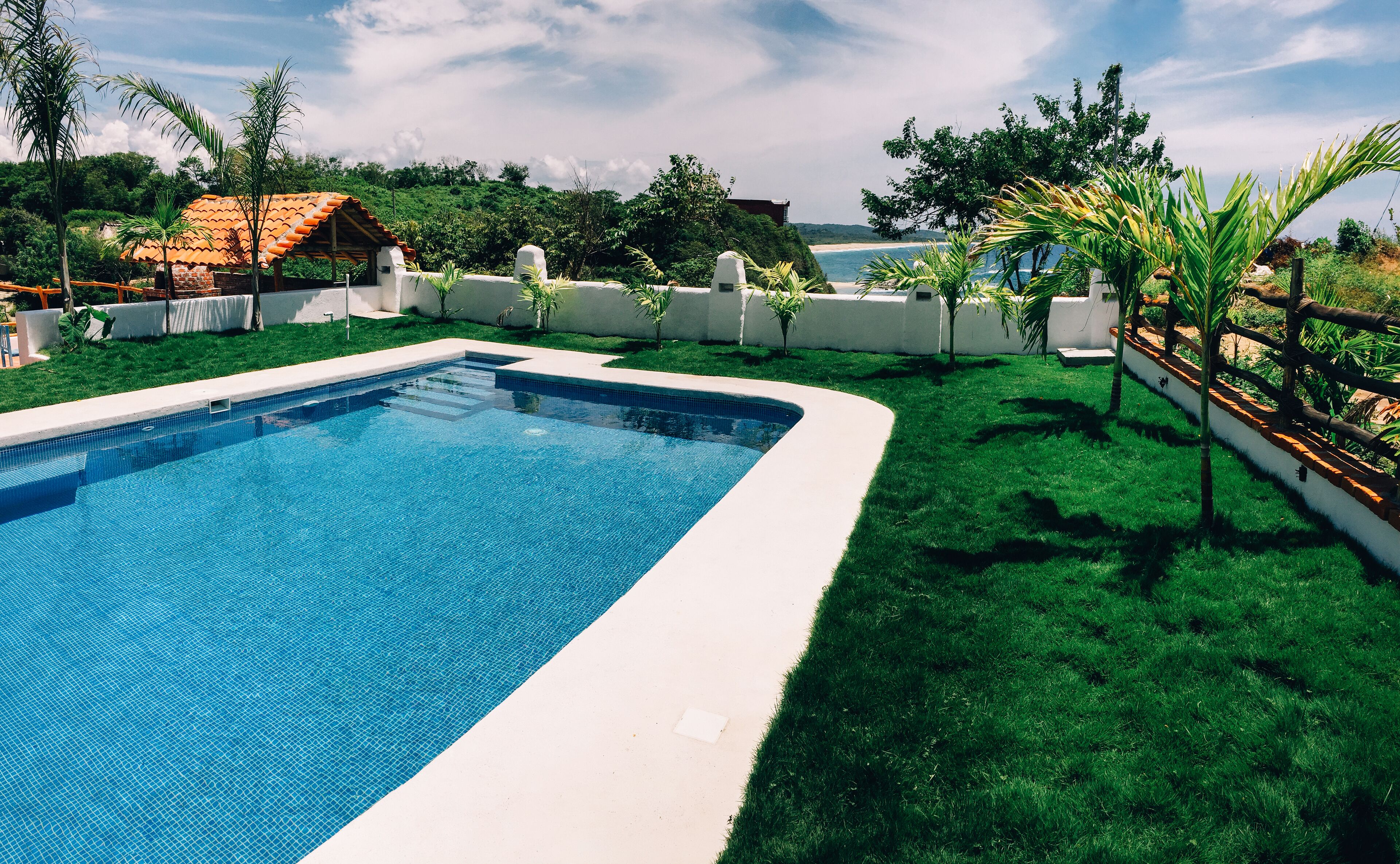 Una piscina al aire libre, sombrillas, sillones reclinables de piscina