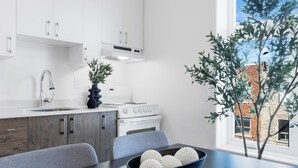 A modern kitchen with white cabinets, a stove, and a dining table with chairs. - LiV MTL - MTL (Montreal)