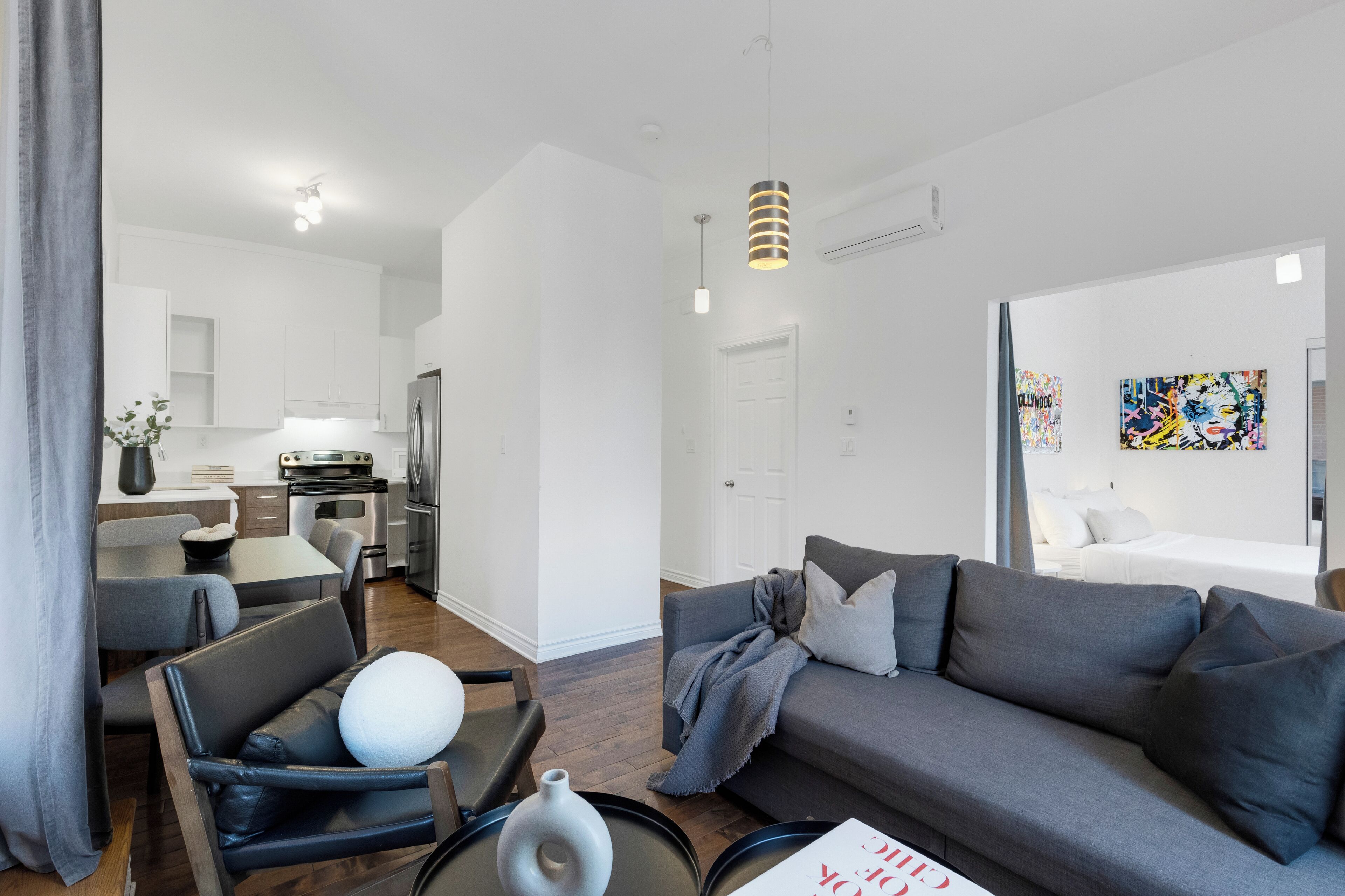 A modern living room with a grey sofa, a coffee table, and a dining area with a table and chairs.