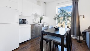 A modern kitchen with white cabinets, a dining table with chairs, a microwave, and a sink. - LiV MTL - MTL (Montreal)