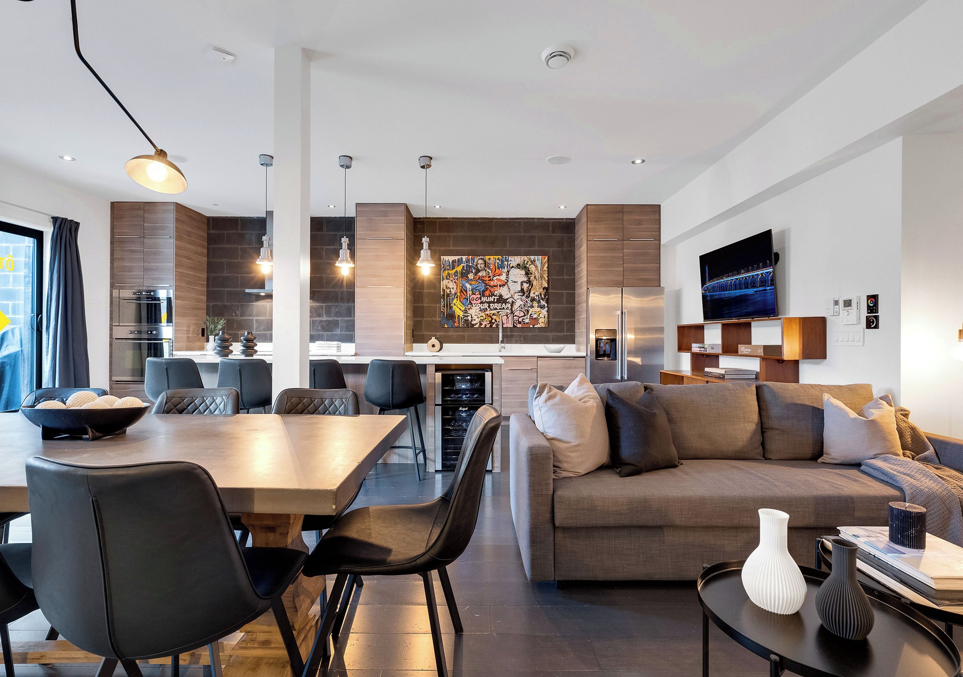 Un salon moderne comprenant un canapé, une table à manger et des chaises. Il y a également un coin cuisine avec un réfrigérateur et un four.