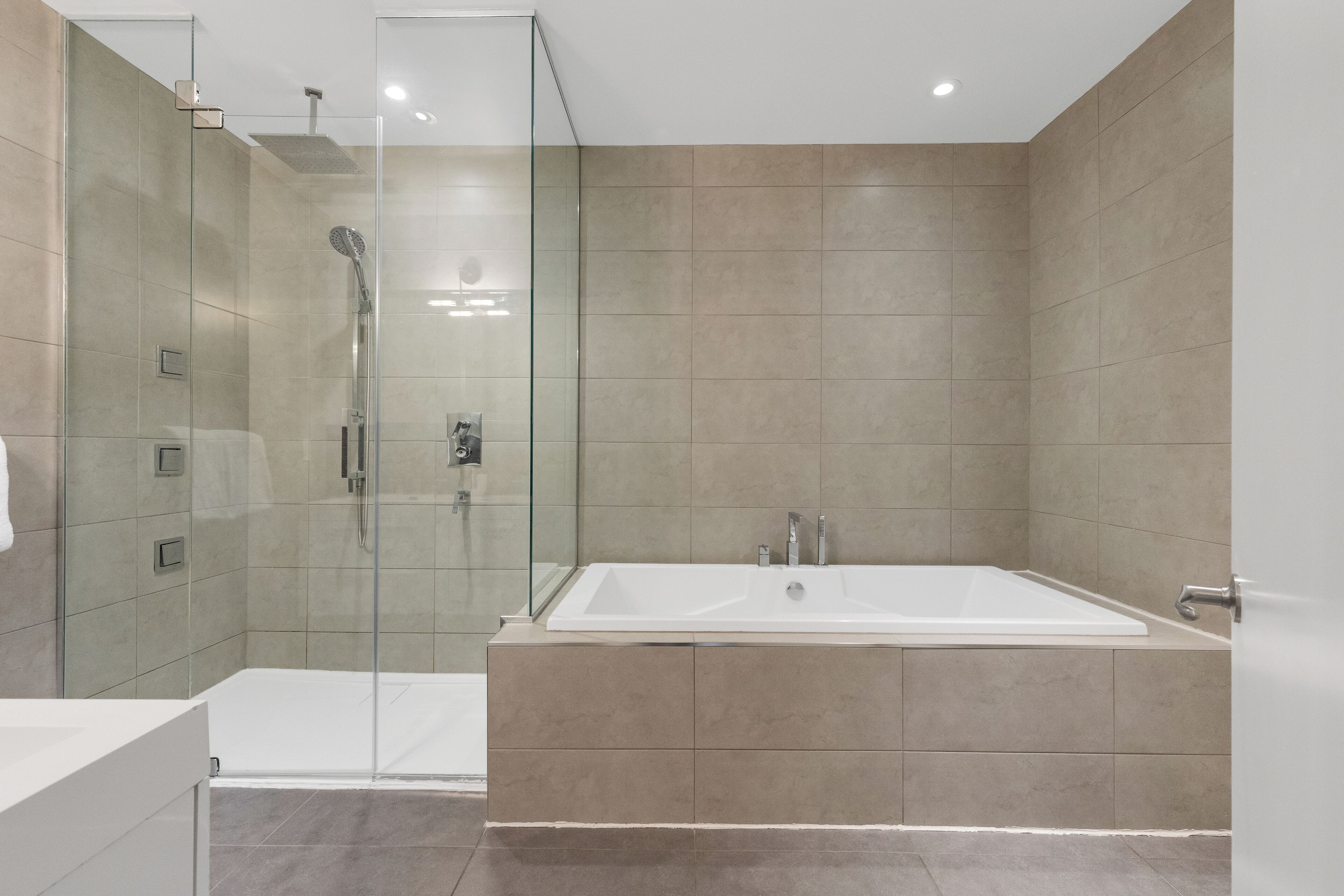 Un bagno moderno con doccia vetrata, una vasca da bagno ampia e un angolo lavabo separato.