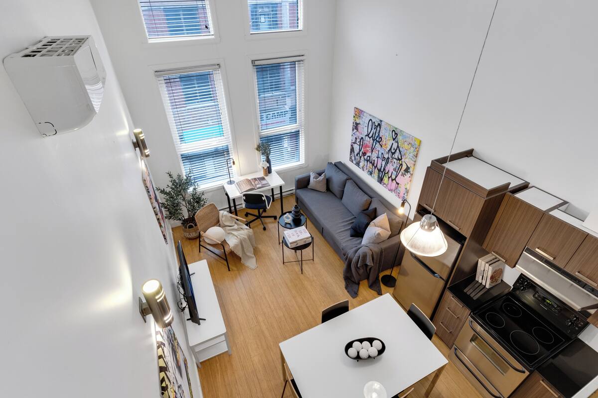 Un apartamento moderno con comedor, sofá, cocina y ventanas amplias.