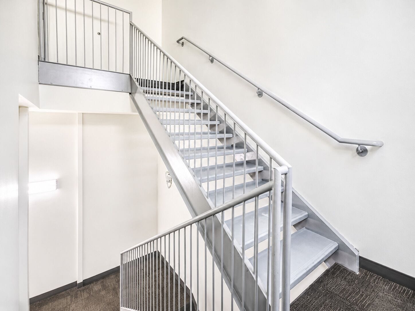 A staircase with metal railings and a carpeted floor.
