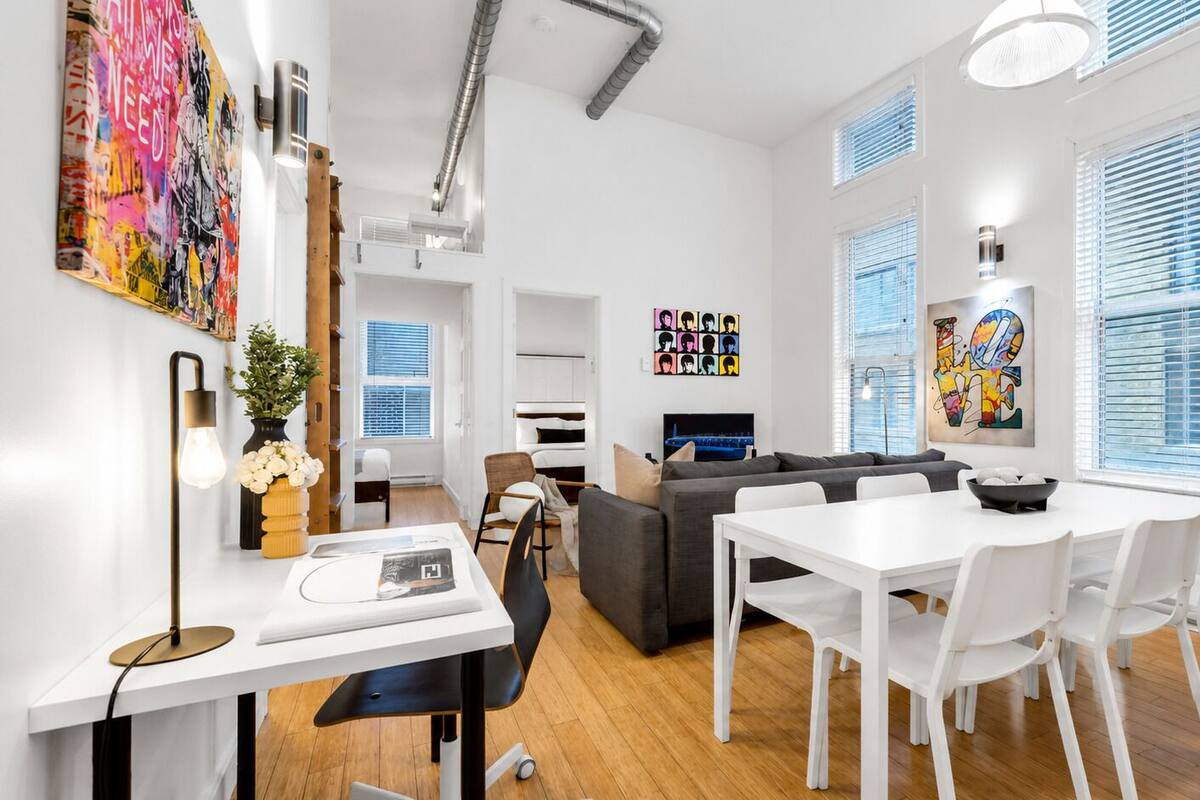 Una sala de estar moderna con comedor, un sofá, un televisor y obras de arte en las paredes.