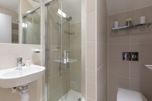A modern bathroom with a glass-enclosed shower, a white sink, and a toilet. - Penthouse View (St Ives)