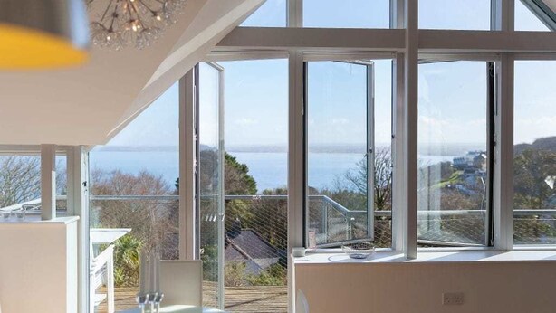 A modern room with large windows offering a view of the sea and surrounding landscape.