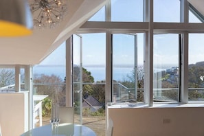Une chambre moderne dotée de grandes fenêtres offrant une vue sur la mer et le paysage environnant.