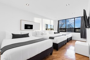 Ein modernes Hotelzimmer mit zwei Betten, einem Fernseher und großen Fenstern mit Blick ins Freie.