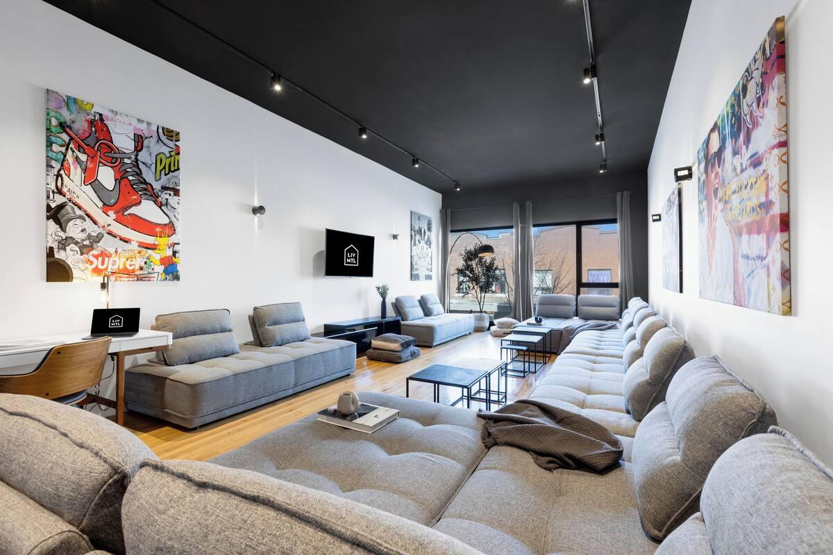 A modern living room with a grey sofa set, a coffee table, and a TV mounted on the wall.