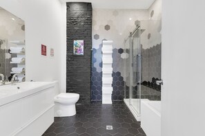 Ein modernes Badezimmer mit Waschbecken, Toilette und Badewanne, alles in Weiß.