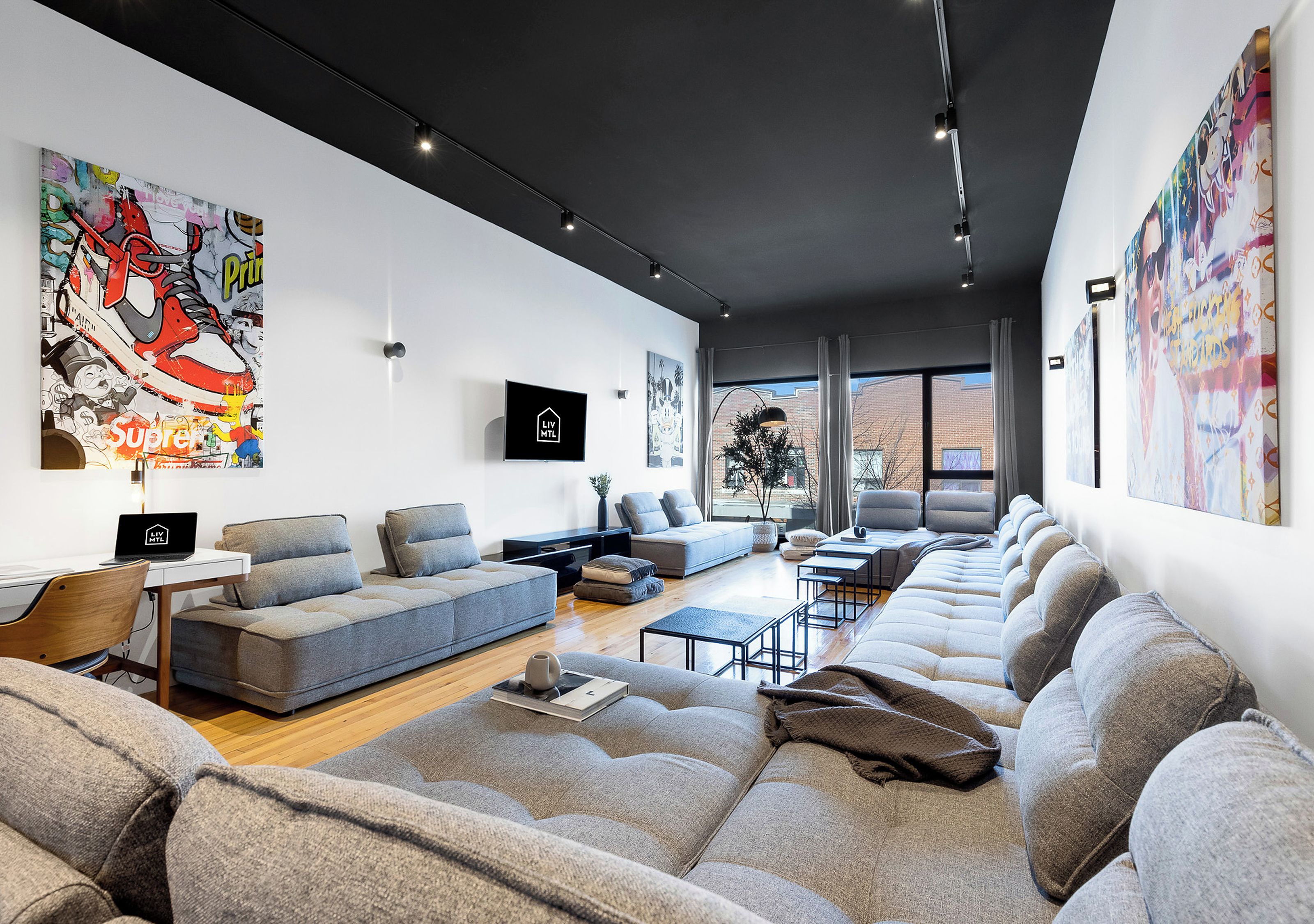 A modern living room with a sofa set, a flat-screen TV, and artwork on the walls.