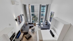 A modern, compact living space with a bed, two sofas, a small coffee table, and a TV. - LiV MTL - Downtown (Montreal)