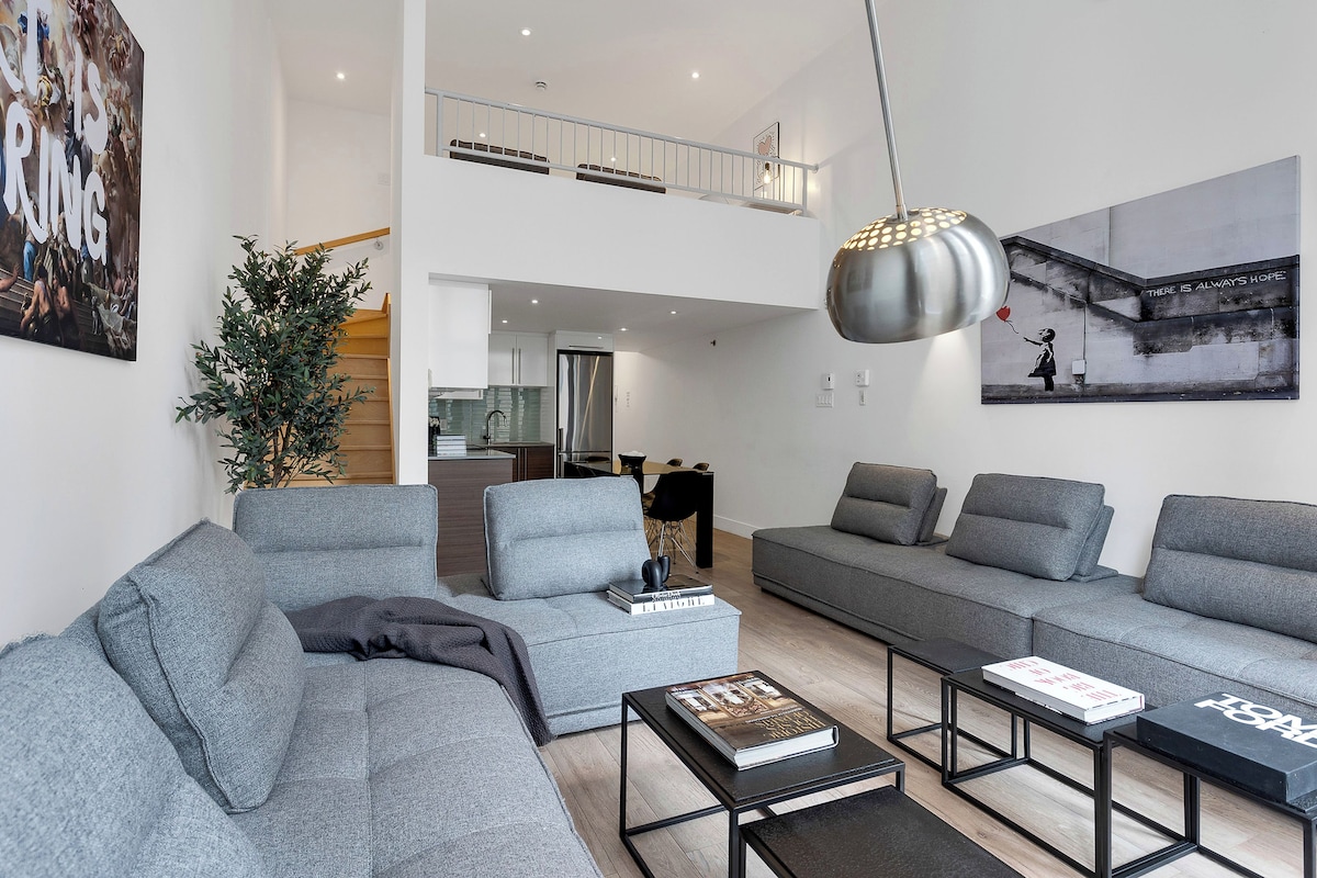 A modern living room with grey sofas, a coffee table, and a hanging light fixture.