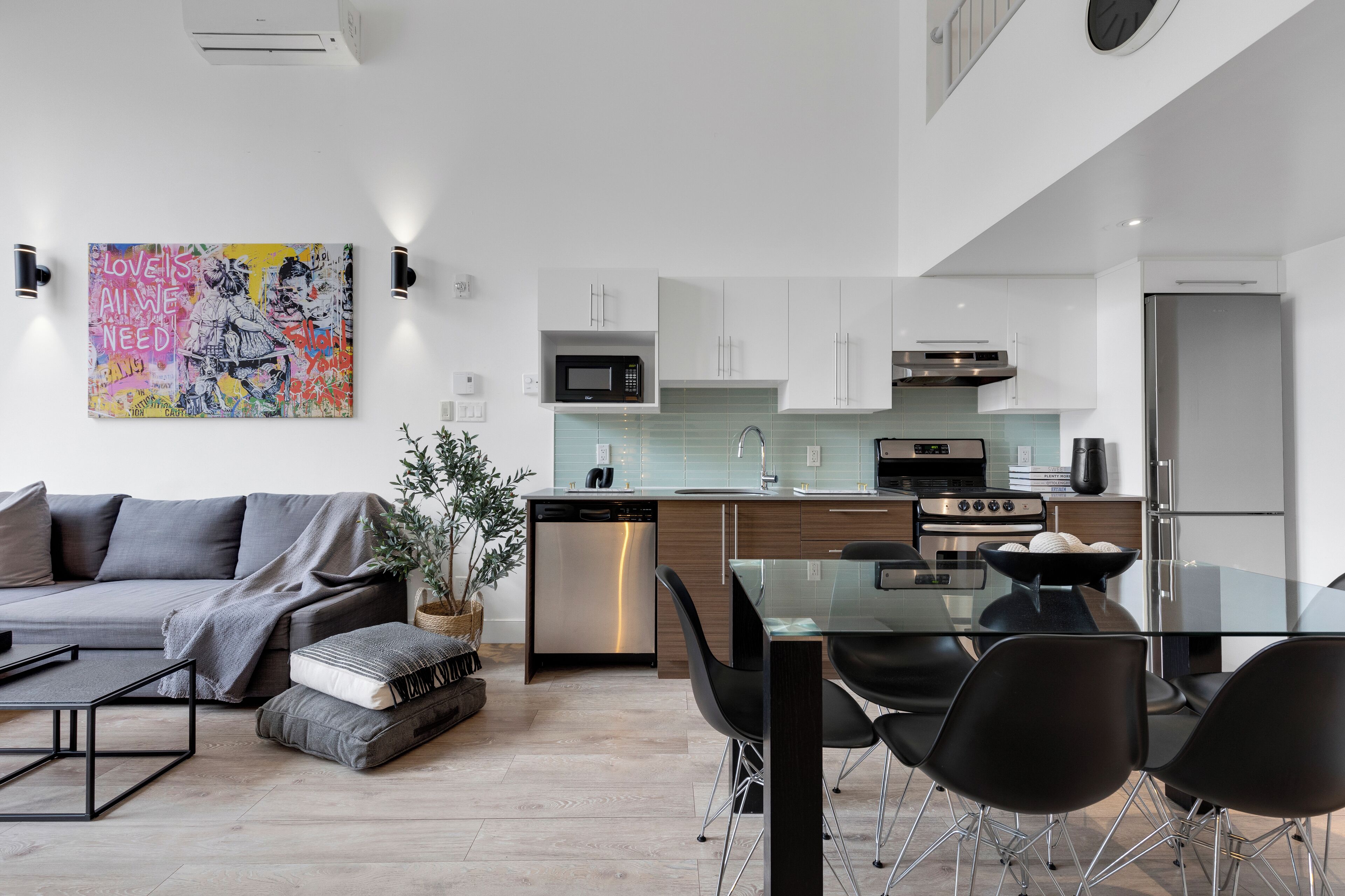 A modern kitchen with white cabinets, stainless steel appliances, and a glass dining table with black chairs.