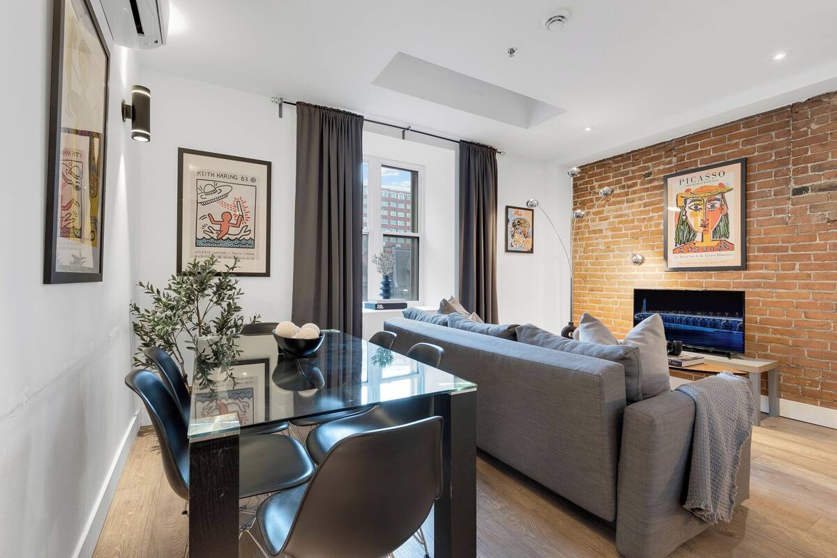 A modern living room with a sofa, TV, and dining area.