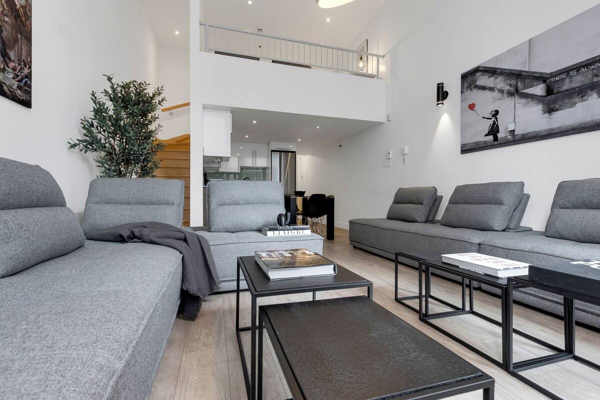 A modern living room with grey sofas, a coffee table, and a bookshelf.