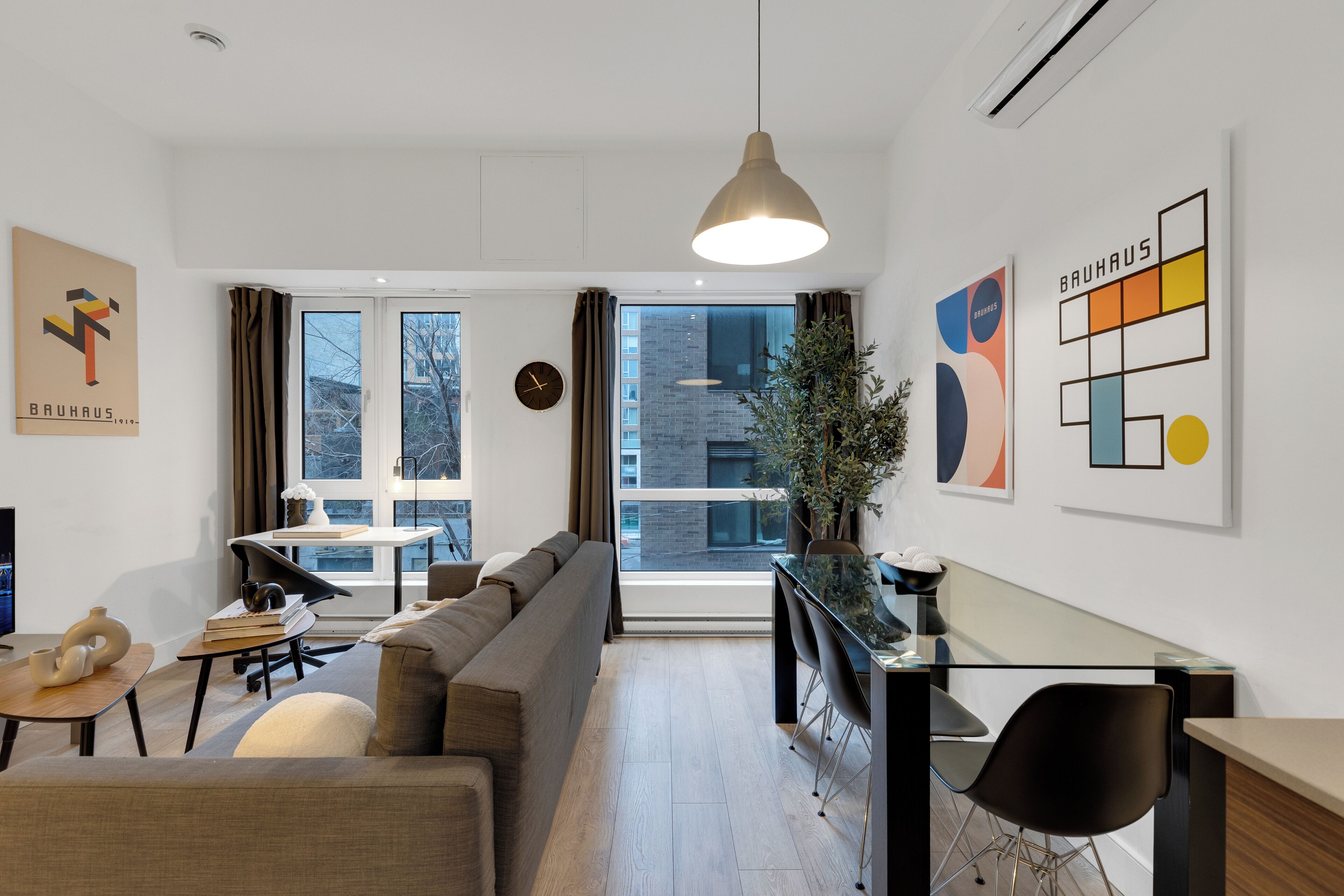 A modern living room with a sofa, a dining area with a glass table, and artwork on the walls.